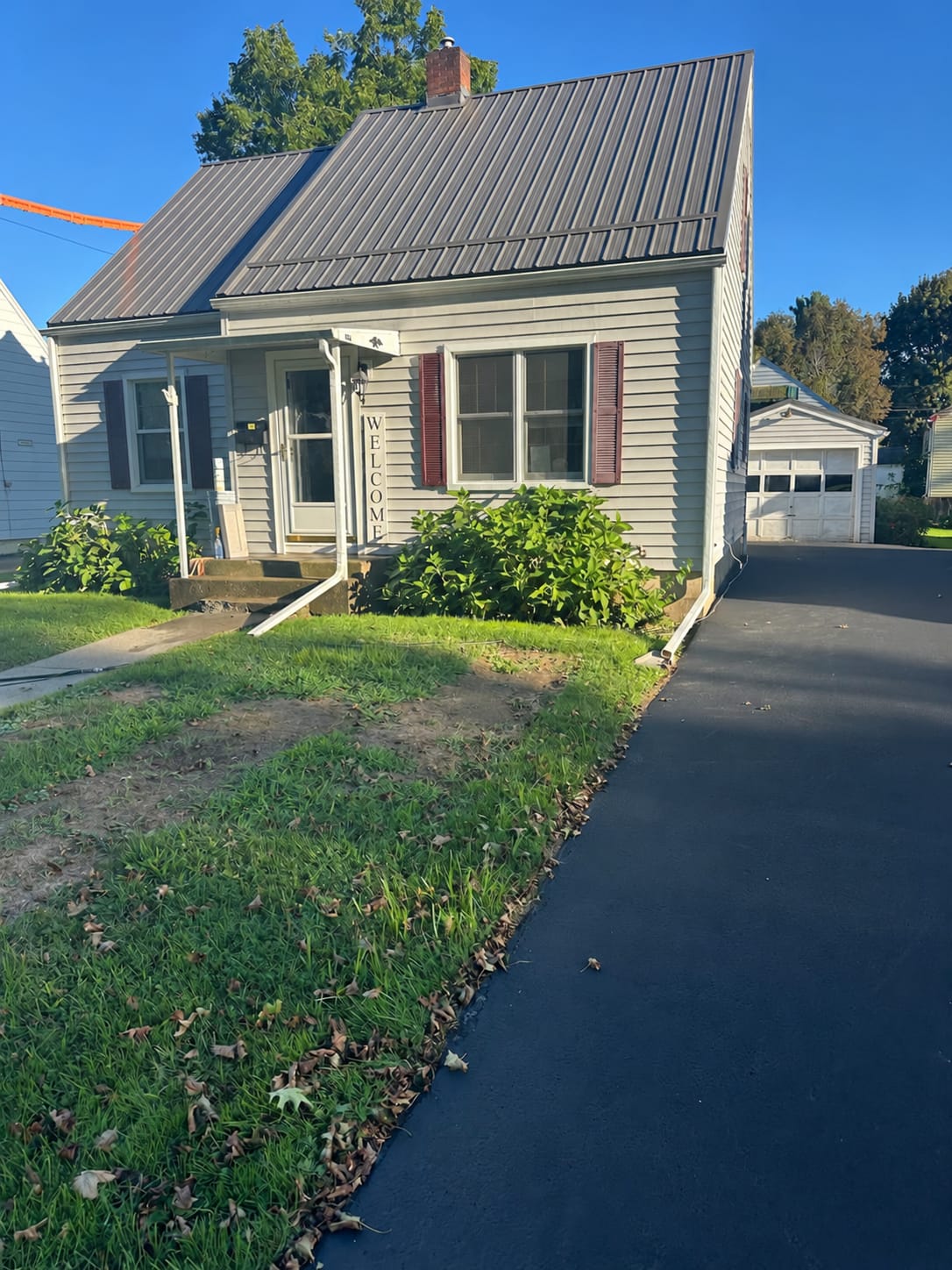 Restored Cape Cod home in Elmira with a metal roof and front lawn